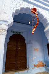 Designer setpiece hanging in front of traditional wooden door and blue coloured house of Jodhpur city, Rajsthan, India. Historically, Hindu Brahmins used to paint their houses in blue.