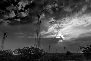 Silhouette of wind mills in twilight with a setting sun and cloudy sky in background, Rajasthan, India