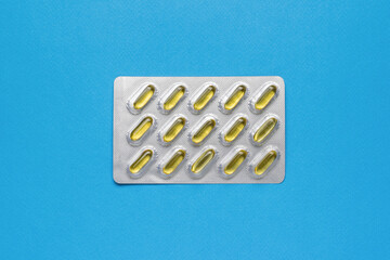 A shiny package with fish oil capsules on a blue background. Biologically active additive.