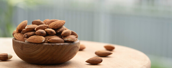 almonds in a wooden bowl on the brown wooden table for banner