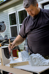 There is worker painting wooden corbels for the kitchen island that are with help of a paintbrush