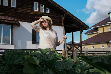 Fototapeta premium A farmer female working in organic greenhouse. Woman growing bio plants, tomatoes and herbs in farm garden. The concept of harvesting. Summer and autumn on the farm.