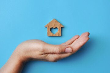 A wooden house in the hands of a man. A symbol of protection and care for home and family