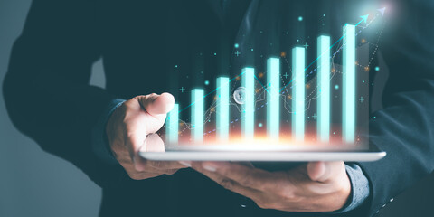 Businessman holding tablet showing growth and progress bar chart from business investment, profit...