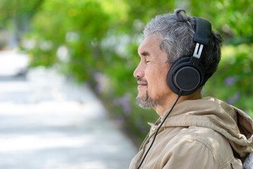 A peaceful mind senior man wearing headphones close eyes focus to listening music or chants while...