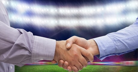 Composition of two businessmen shaking hands over sports stadium