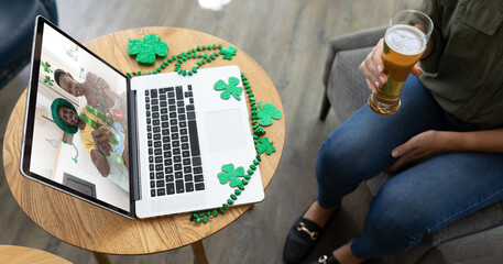Caucasian woman at bar holding beer making st patrick's day video call to friends on laptop