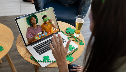 Caucasian woman at bar making st patrick's day video call waving to male friends on laptop