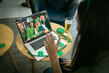 Caucasian woman at bar making st patrick's day video call waving to friends in costume on laptop