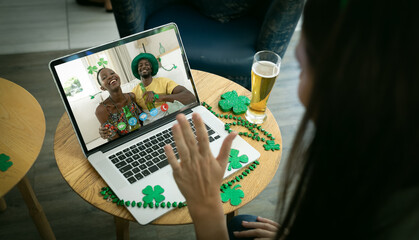 Caucasian woman at bar making st patrick's day video call waving to smiling couple on laptop screen