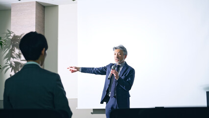 登壇する男性と聴衆　セミナー　プレゼンテーション
