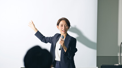 登壇する女性と聴衆　セミナー　プレゼンテーション