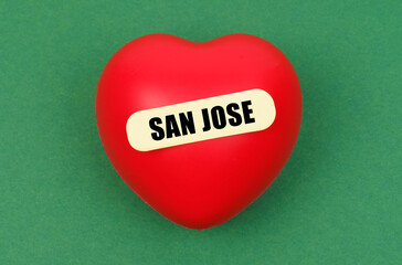 On a green surface lies a red heart with the inscription - San Jose