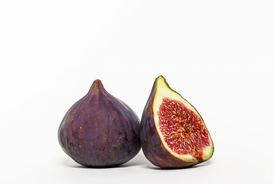 Ripe figs and half of the fruit on a white background.