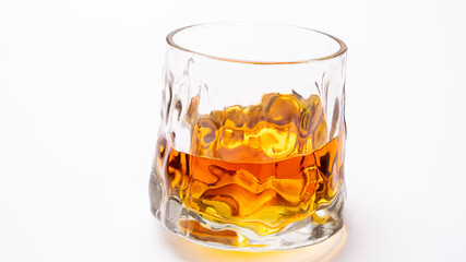 Close-up of golden yellow whiskey set on white background.