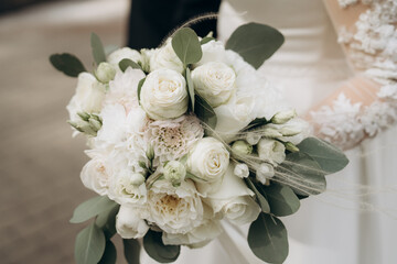 Beautiful bride holds white bouquet. bouquet from white rosses in woman's hands