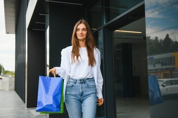 woman holding shopping bags of luxury brands, walking near shopping mall