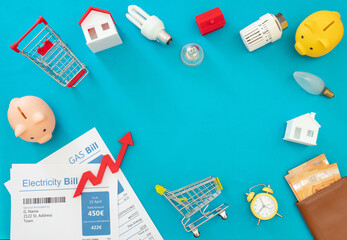 Living cost increase flat lay. Shopping cart utilities bills on blue background.