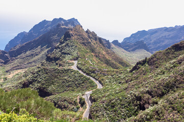 Aerial panoramic view on narrow winding curvy mountain road to remote village Masca, Teno mountain massif, Tenerife, Canary Islands, Spain, Europe. Massive steep rock formation Roque de la Fortaleza