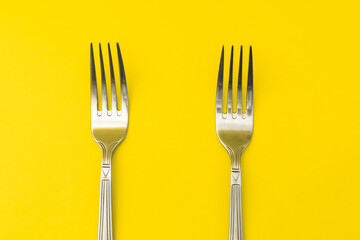Silver forks lie on a yellow background, minimalism