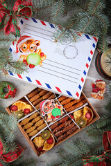 Pastille of fruits and berries in a box. The festive box is decorated in the form of a postal envelope. Spruce branches. The concept of New Year's gifts. A watch with Roman dial.Flat lay.Top view.
