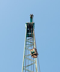 Large green crane boom with hooks with blue sky background