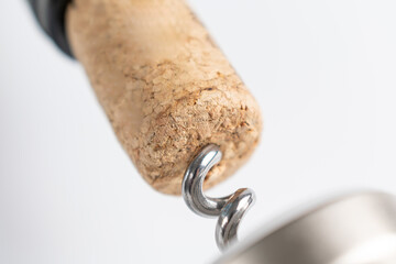Close up of a corkscrew opening a bottle of wine. The cork is pierced by the metal spiral of the...