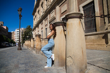 Fototapeta na wymiar Beautiful young woman in casual clothes leaning on a column in the cathedral of Seville. The woman is on tourism enjoying her holidays in Spain. Travel concept.