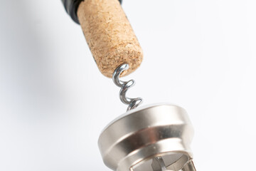 Close up of a corkscrew opening a bottle of wine. The cork is pierced by the metal spiral of the...