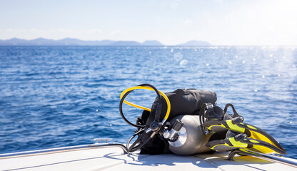 Concept of scuba diving with tank and equipment lying on a boat over blue sea and sunshine