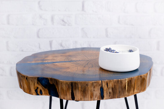 Wooden table with epoxy resin. Decorative candle on the table. Against the background of brick resin.