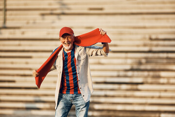 Cheerful senior sports fan outdoor looking at camera. Copy space.