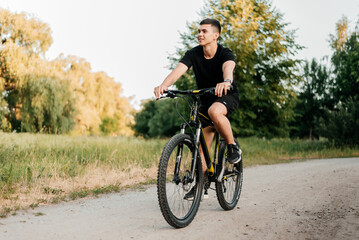 A man rides a bicycle along a path in the park