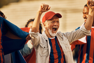 Excited senior soccer fan cheering for his team during sports championship.