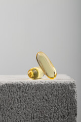 Yellow oil capsules with vitamin D on grey background. Omega 3 tablet. Healthy diet concept