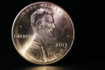 Closeup of In God We Trust Lincoln coin isolated on a black background - obrazy, fototapety, plakaty