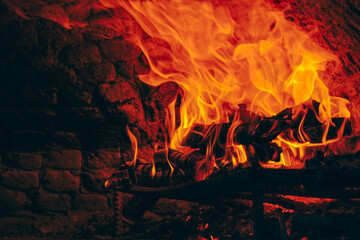 Wood fire in yellow and red colors burning in stone oven, copy space.