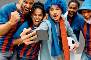 Obraz premium Close up of soccer fans watching live stream of match on smart phone.