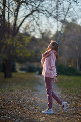 Fototapeta premium A girl in a knitted sweater in an autumn park. September or October, yellow leaves on trees.