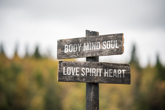 vintage and rustic wooden signpost with the weathered text quote body mind soul love spirit heart, outdoors in nature.