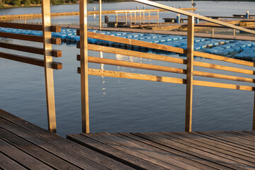 Close-up of the wooden railing of the pier, in the evening at sunset on the background of a pond...