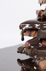 chocolate sauce flowing over chocolate pieces on white background