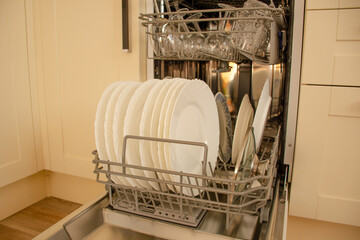 Clean dishes in the new dishwasher in the kitchen. The concept of home interior and comfort