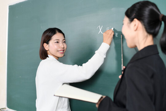 黒板に記入する女子学生と先生（講師）