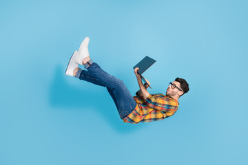 Full length profile photo of falling flying person hold use wireless netbook isolated on blue color...
