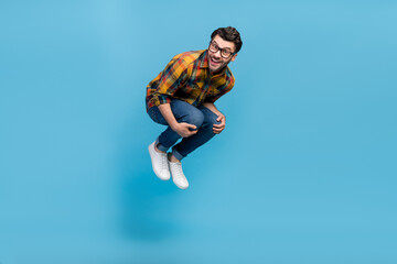 Full body photo of overjoyed glad person jumping falling toothy smile isolated on blue color background