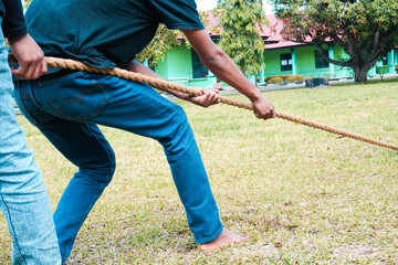 A man's hand holds a rope. Get ready for the tug of war match. Person with rope on the field