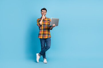 Full size photo of cheerful minded man arm touch chin use netbook isolated on blue color background