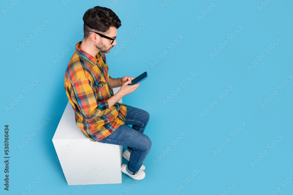 Wall mural full body above view profile portrait of focused man sit hold use telephone isolated on blue color b