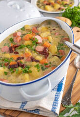 Pot with potato soup or stew with crispy bacon and vienna sausage